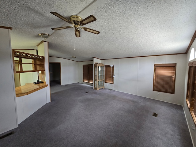 unfurnished living room with carpet, ornamental molding, vaulted ceiling, a textured ceiling, and ceiling fan