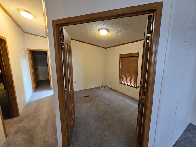 interior space featuring carpet, visible vents, ornamental molding, and a textured ceiling