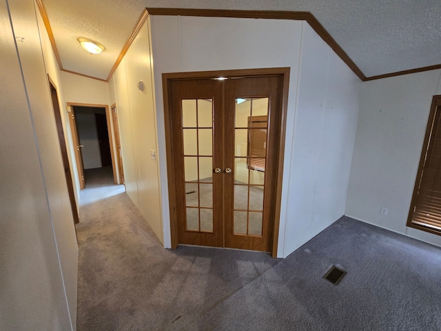 hallway with carpet floors, visible vents, a textured ceiling, and french doors