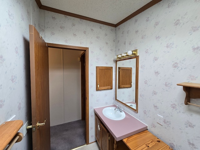 bathroom featuring a textured ceiling, crown molding, vanity, and wallpapered walls