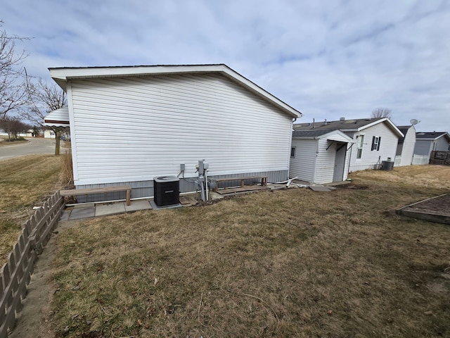 view of side of property featuring central AC and a lawn