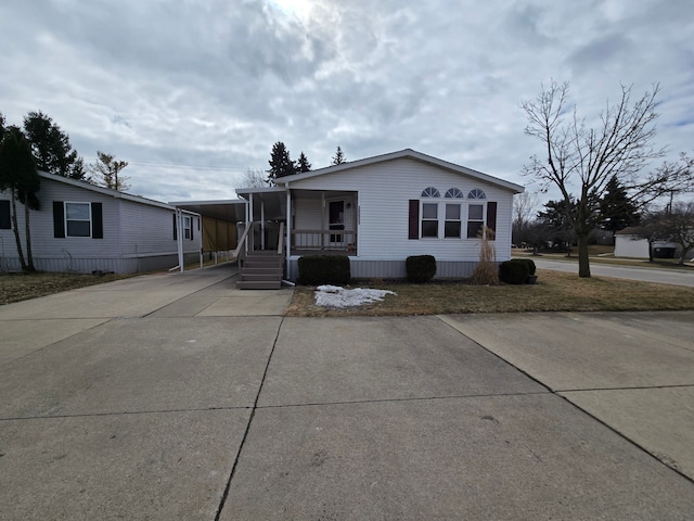 view of front of home with concrete driveway, a porch, and an attached carport