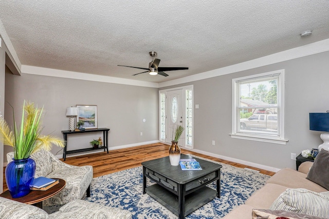 living room featuring a ceiling fan, a textured ceiling, baseboards, and wood finished floors