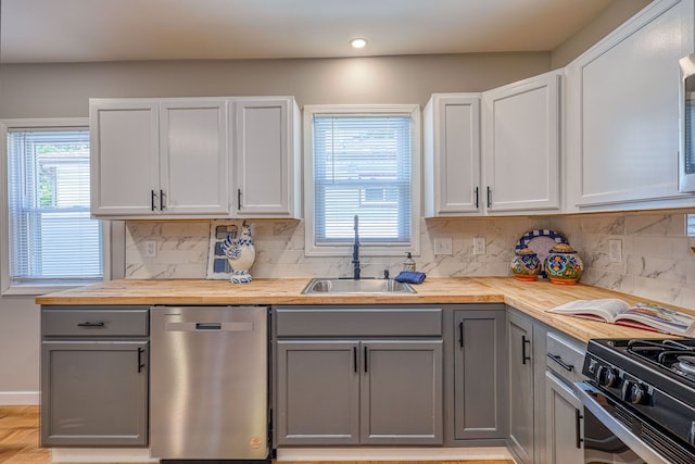 kitchen with a sink, wooden counters, stainless steel dishwasher, and gray cabinetry