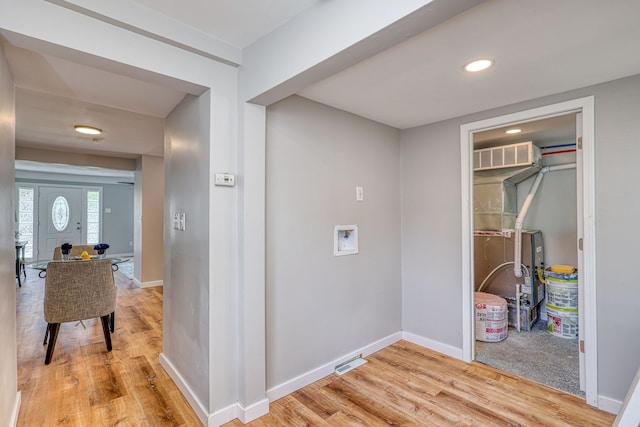 hall with visible vents, light wood-style flooring, and baseboards