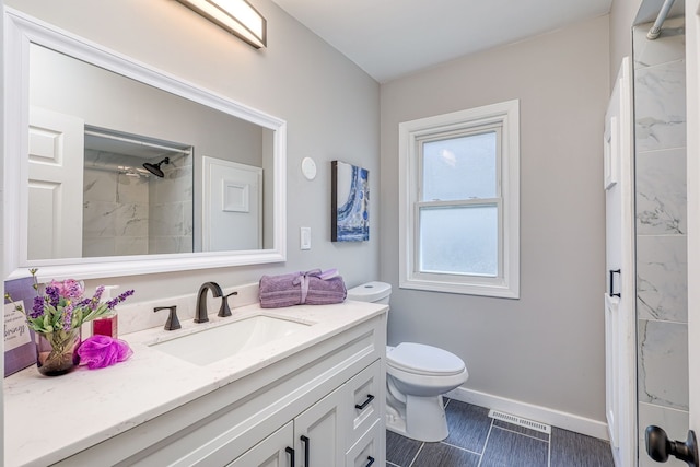 bathroom featuring toilet, visible vents, vanity, baseboards, and a tile shower