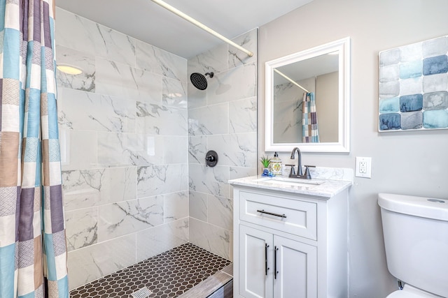 full bath featuring toilet, tiled shower, and vanity