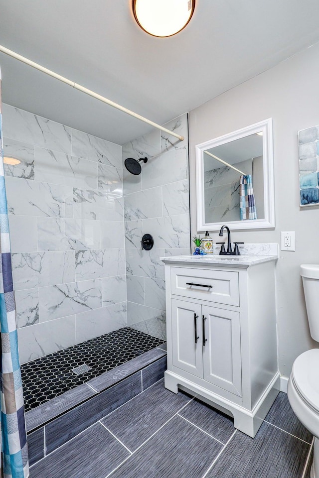 full bathroom with baseboards, a tile shower, vanity, and toilet