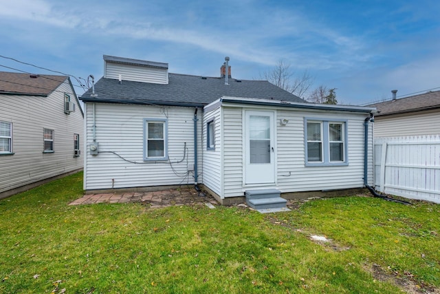 rear view of property with a shingled roof, entry steps, a yard, and fence