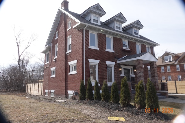 view of front of house with fence, brick siding, and a chimney