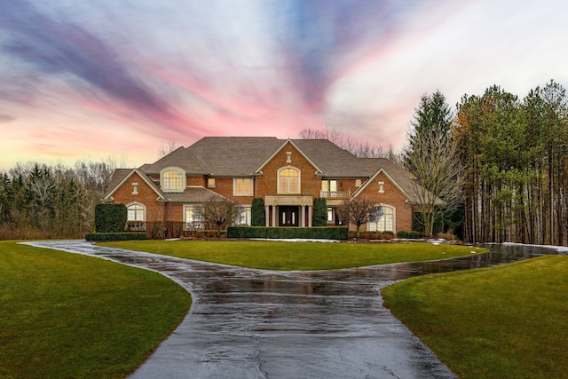 view of front facade featuring a yard, driveway, and brick siding