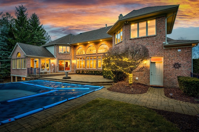 back of house featuring brick siding, a patio, a chimney, and a covered pool