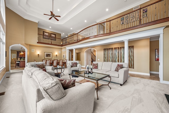 living area with a towering ceiling, arched walkways, carpet flooring, and ornamental molding