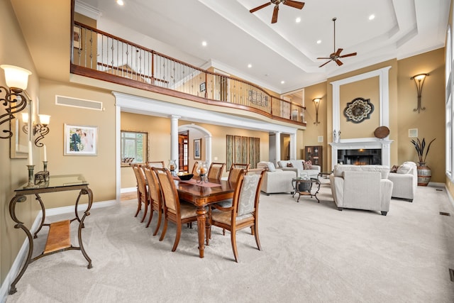 dining space with light carpet, visible vents, baseboards, a lit fireplace, and ornate columns