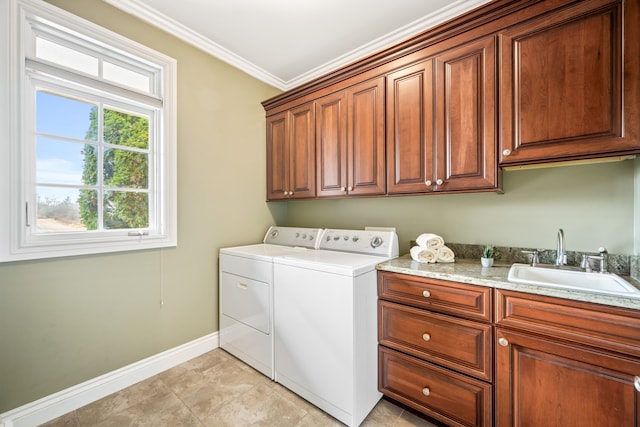 washroom featuring a sink, baseboards, washer and dryer, cabinet space, and crown molding