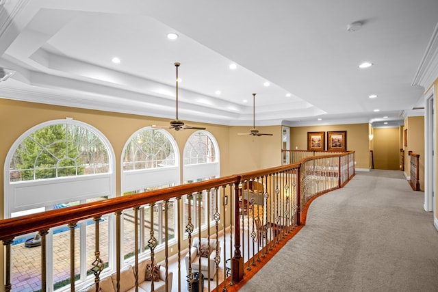 hall with a tray ceiling, a wealth of natural light, and recessed lighting