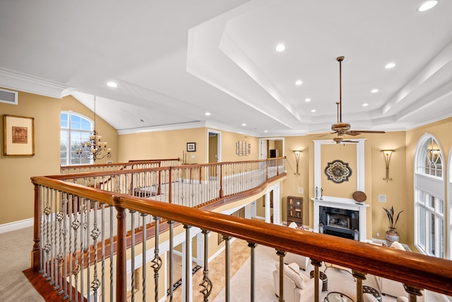 hall with recessed lighting, a tray ceiling, ornamental molding, and an upstairs landing