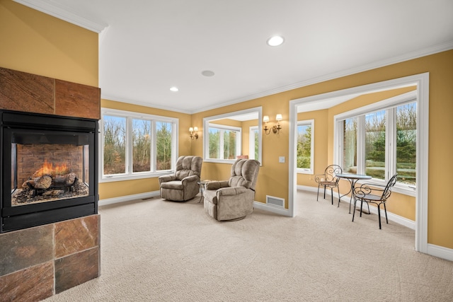 sitting room with carpet, crown molding, visible vents, a tiled fireplace, and baseboards