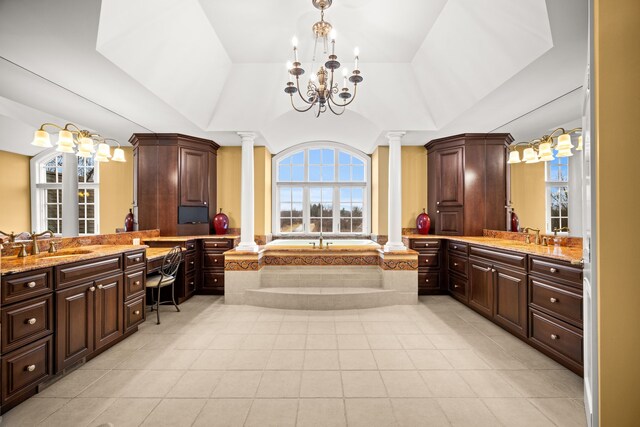 bathroom featuring a raised ceiling, two vanities, a sink, and decorative columns