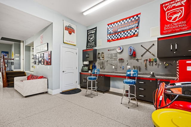 miscellaneous room with speckled floor, a workshop area, and baseboards