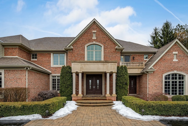 view of front facade featuring french doors, brick siding, and a shingled roof