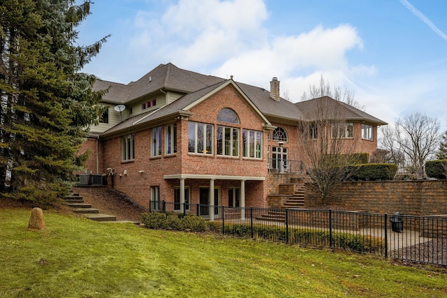 back of house with brick siding, a chimney, a lawn, stairway, and fence private yard