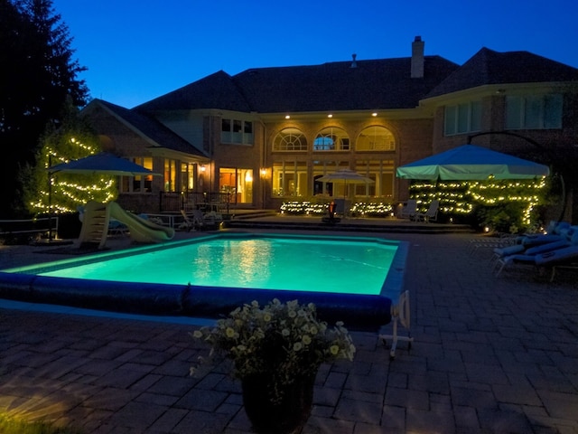 pool with a patio and a water slide