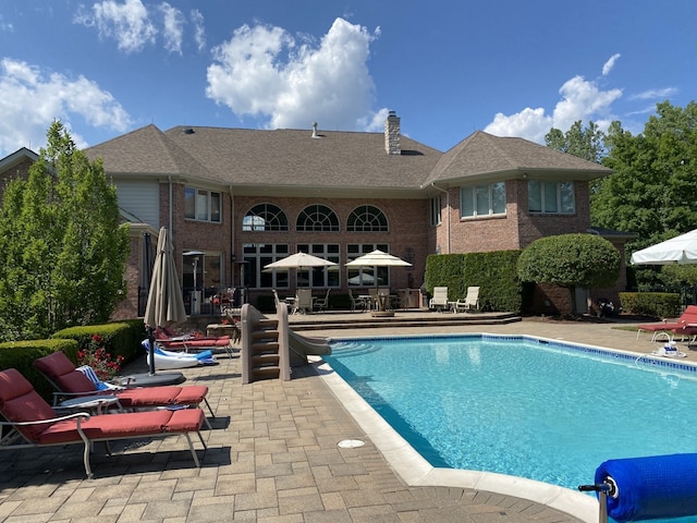 outdoor pool with a water slide and a patio