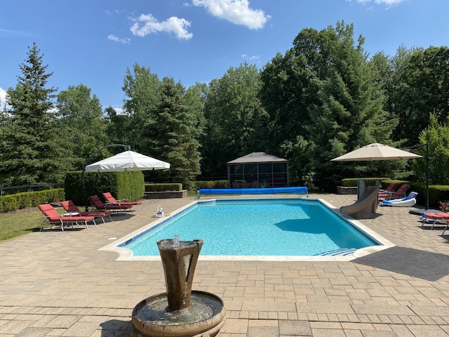 view of swimming pool featuring a water slide, a patio area, and a fenced in pool