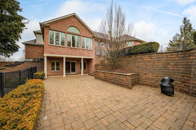 rear view of property with brick siding, stairway, a patio area, and a fenced backyard