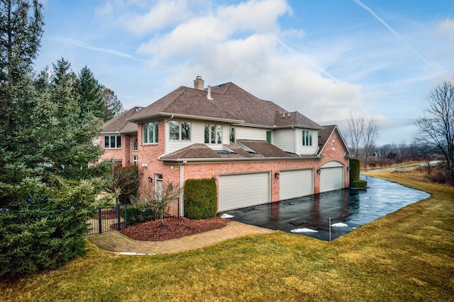 view of front of home with a front yard, brick siding, driveway, and a chimney