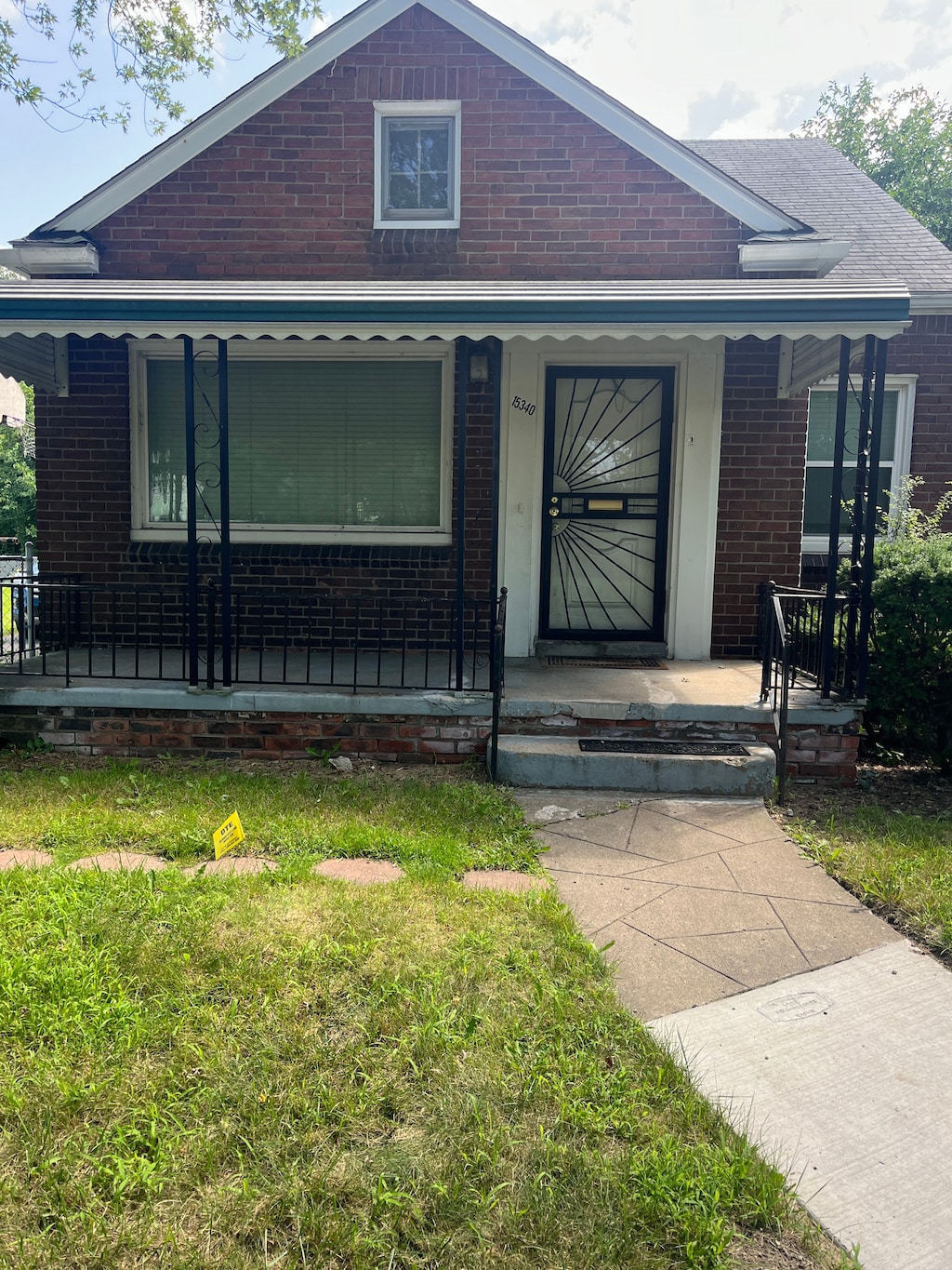 bungalow-style house with covered porch, brick siding, and a front yard