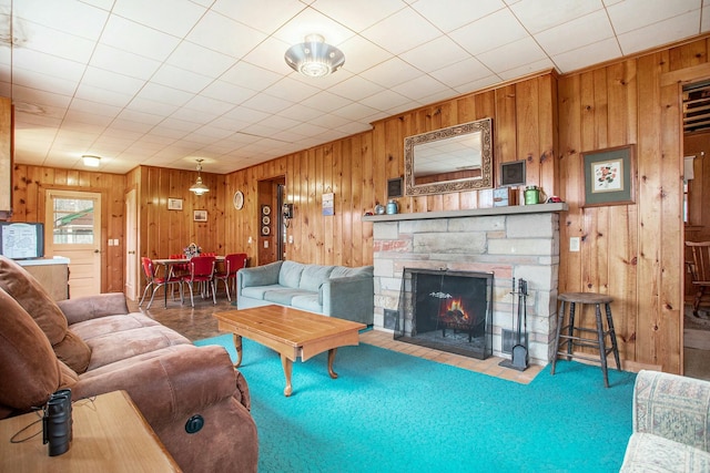 living area with a stone fireplace and wooden walls