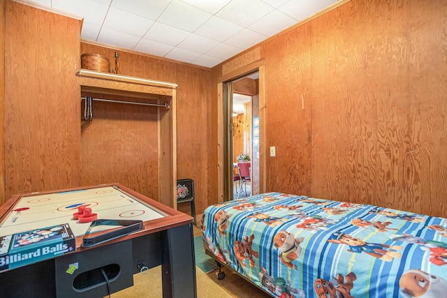 bedroom featuring carpet, crown molding, wooden walls, and a closet