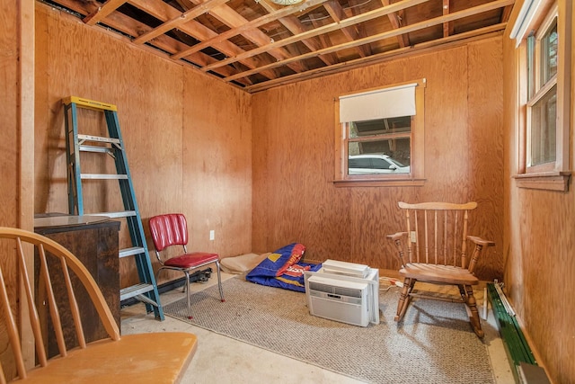 living area featuring a baseboard heating unit, a wall unit AC, and unfinished concrete flooring