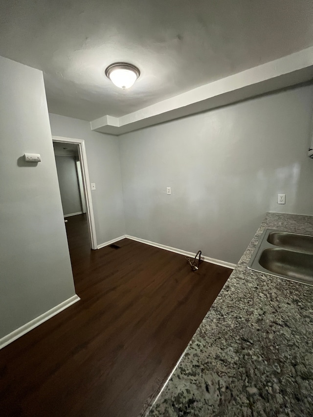interior space with dark wood-type flooring, a sink, and baseboards