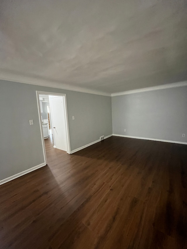 unfurnished room featuring ornamental molding, baseboards, visible vents, and dark wood finished floors
