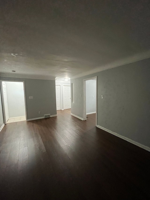 spare room with baseboards and dark wood finished floors