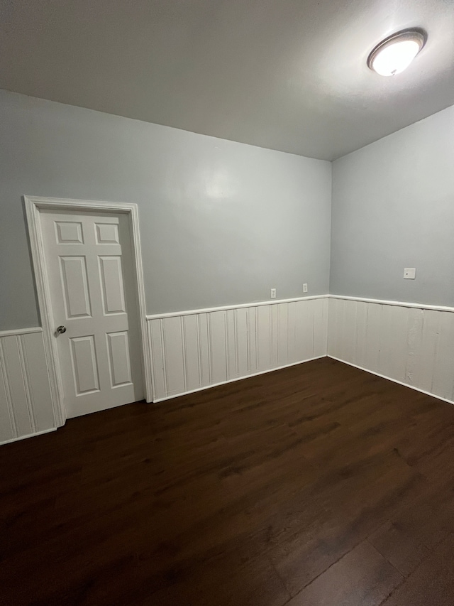 empty room featuring wainscoting and dark wood finished floors