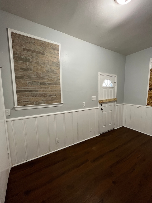 spare room featuring dark wood-style flooring and wainscoting