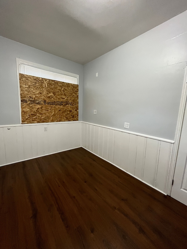 unfurnished room with a wainscoted wall and wood finished floors