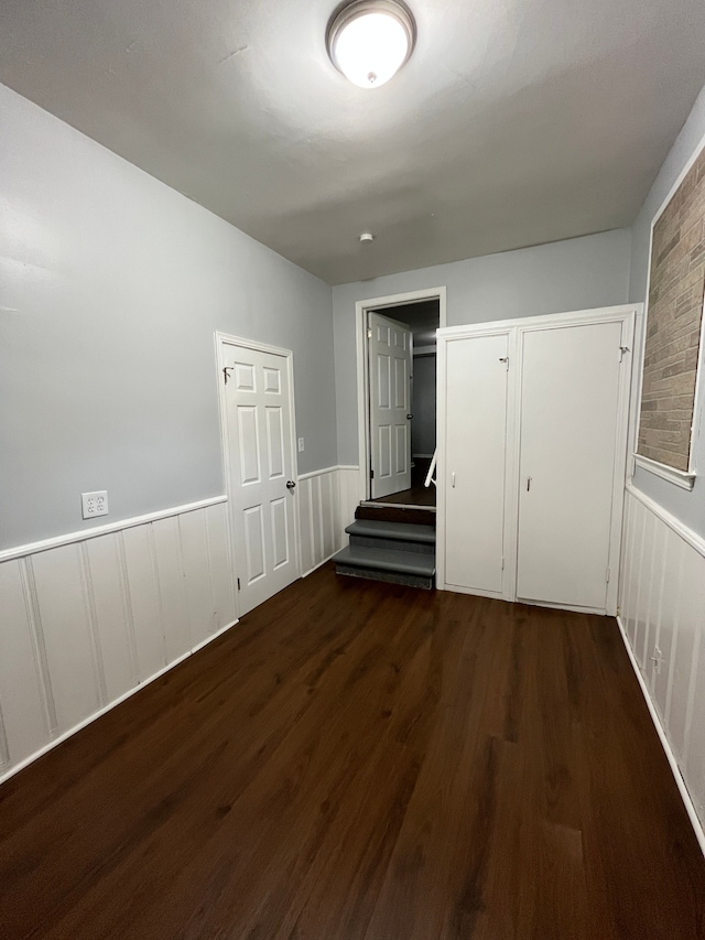 unfurnished bedroom featuring wainscoting and wood finished floors