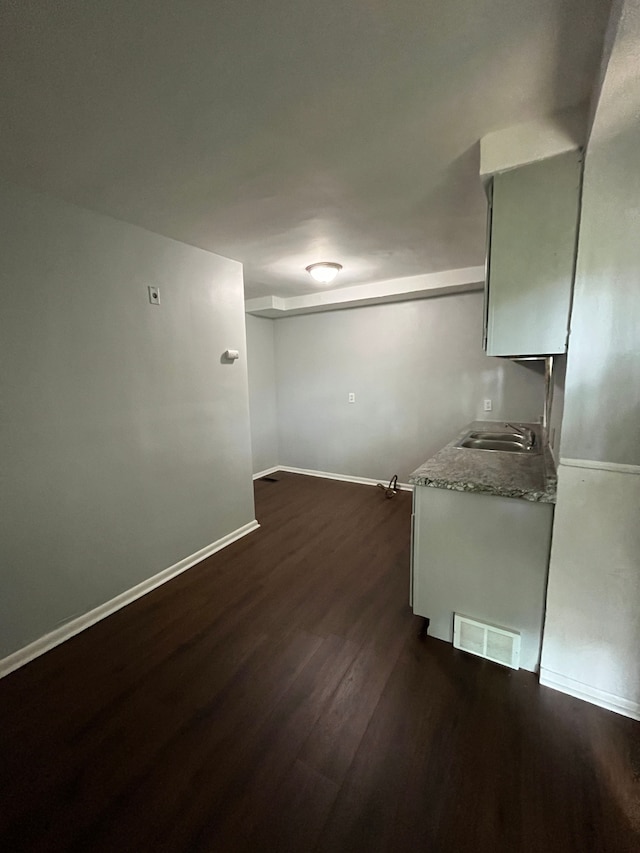 kitchen featuring baseboards, dark wood-style floors, light countertops, visible vents, and a sink