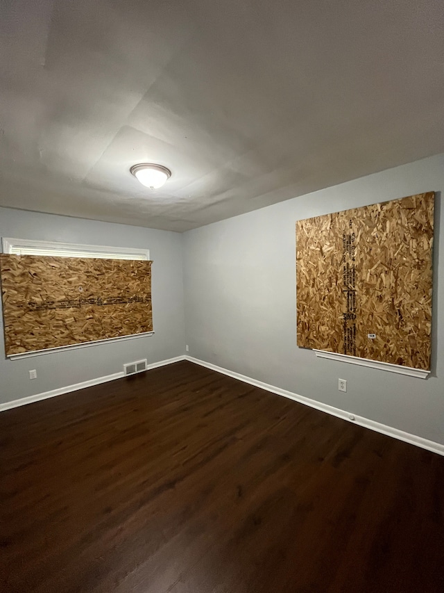 spare room with visible vents, baseboards, and dark wood-style floors