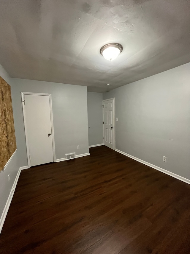 spare room featuring dark wood-type flooring, baseboards, and visible vents