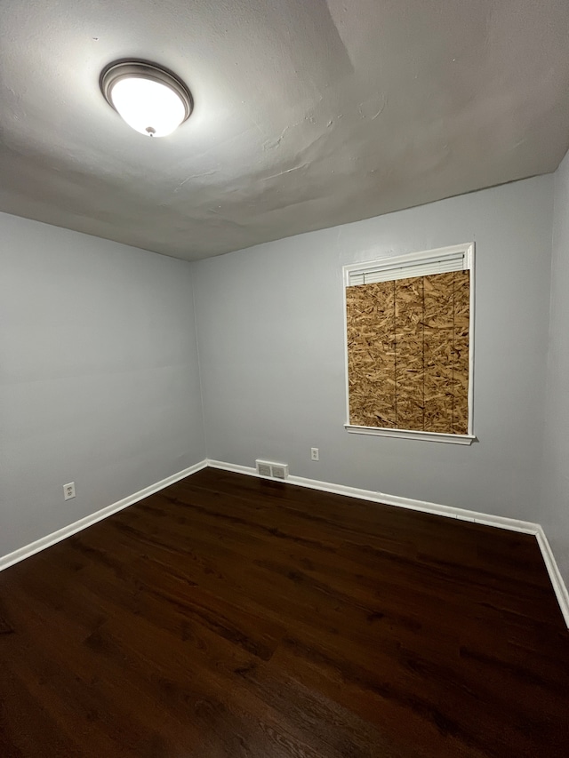 spare room featuring visible vents, baseboards, and wood finished floors