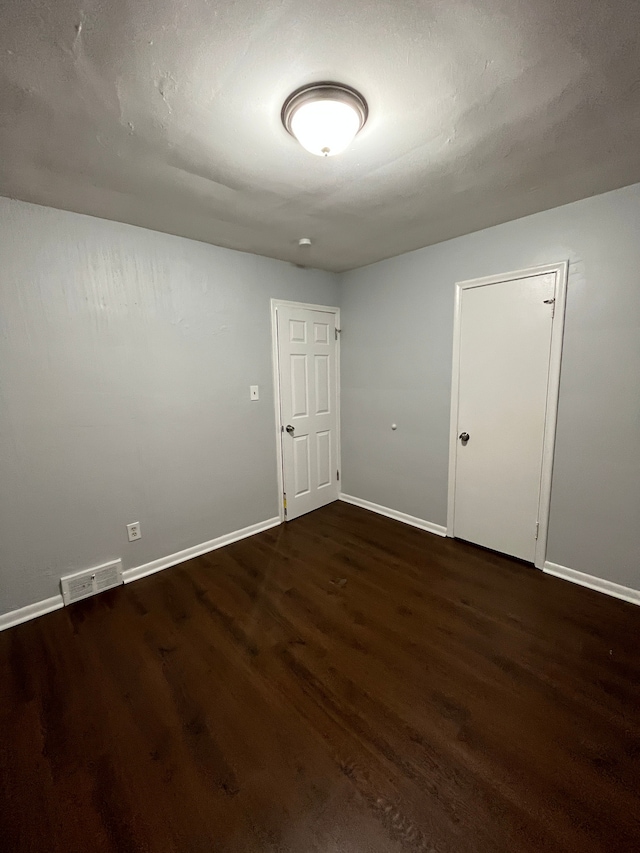 unfurnished room featuring visible vents, baseboards, and wood finished floors