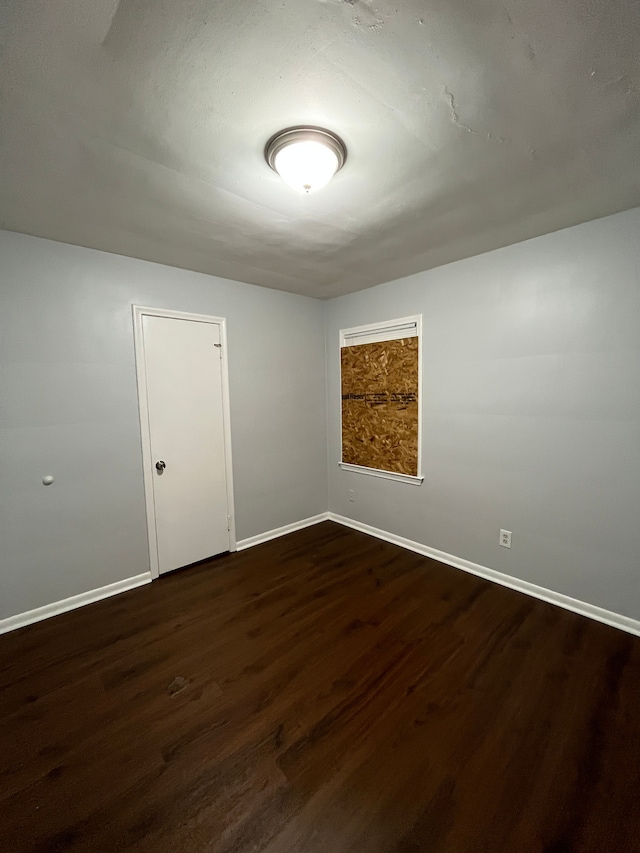 empty room featuring dark wood-style flooring and baseboards
