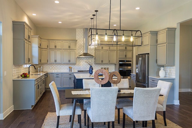 kitchen with wall chimney exhaust hood, a kitchen island, dark wood-style flooring, stainless steel appliances, and gray cabinetry