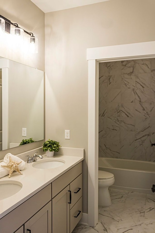 bathroom with marble finish floor, a sink, toilet, and double vanity